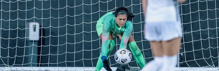 Female soccer playeer in green uniform diving for ball