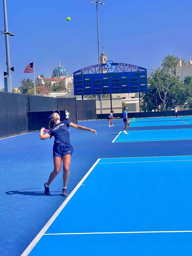 Female tennis player jumping up to hit the ball