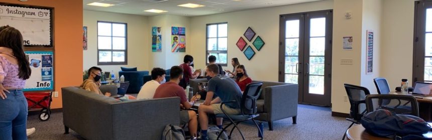 Inside of a common area on campus with students sitting on couches and chairs
