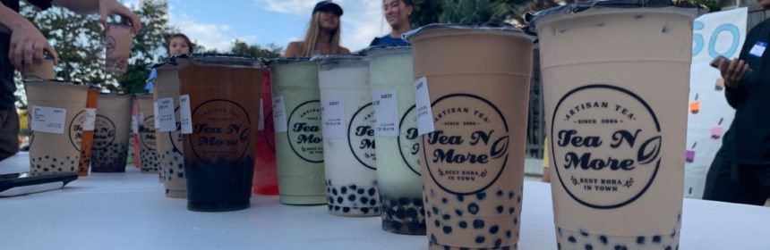 Multiple plastic cups of boba tea drinks lined up on a table