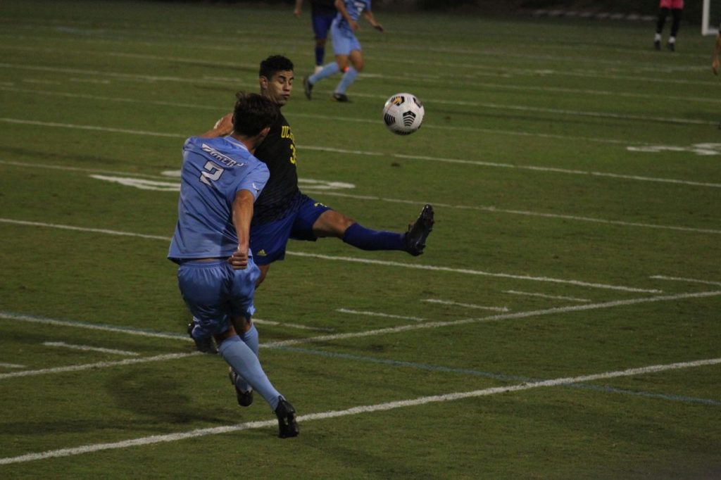 Action shot of men's soccer game after one player kicks the ball into the air