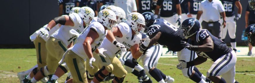 Football players from opposing teams running towards each other on a field