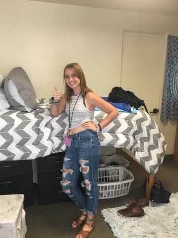 Female standing in front of dorm room bed