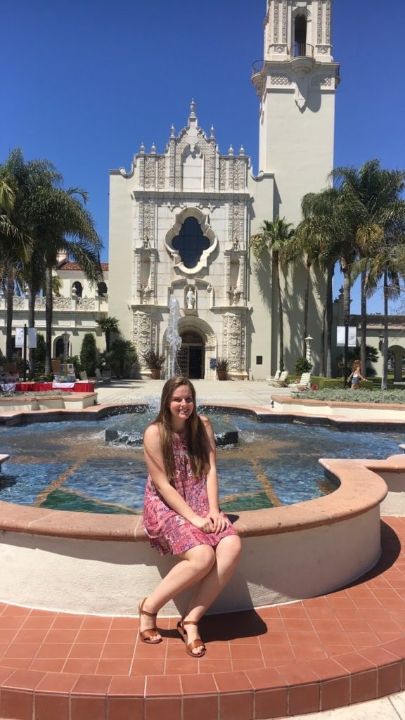 Female sitting on edge of fountain in front of church
