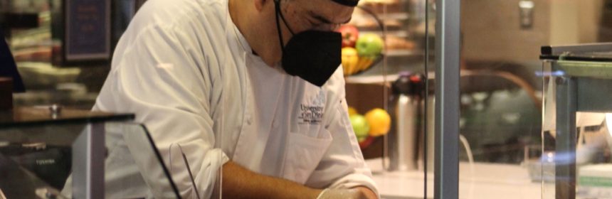 Chef wearing black face mask cooking on hot grill top