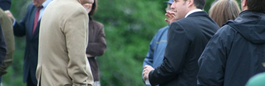Men in suits outdoors speaking to each other