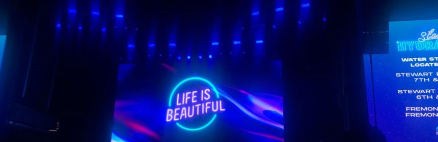Neon concert lights reading "Life Is Beautiful"