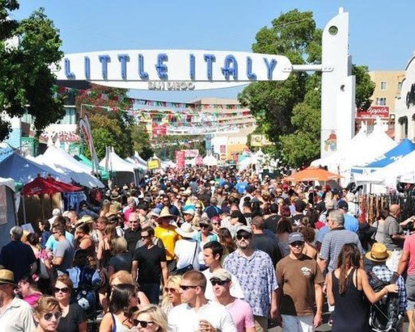 Farmers market packed with people and sign overhead reading "Little Italy"