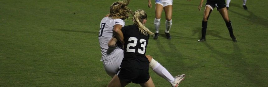 Two soccer players fight for the ball on field during game