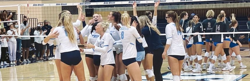 Female volleyball players celebrating together during a game