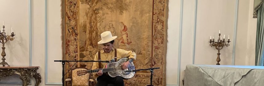Man in ornate room playing the guitar