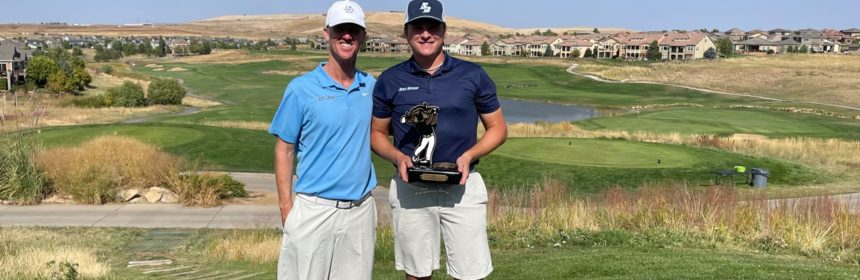 Two men standing on golf course holding trophy
