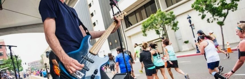Man playing the guitar on the sidelines of a street marathon