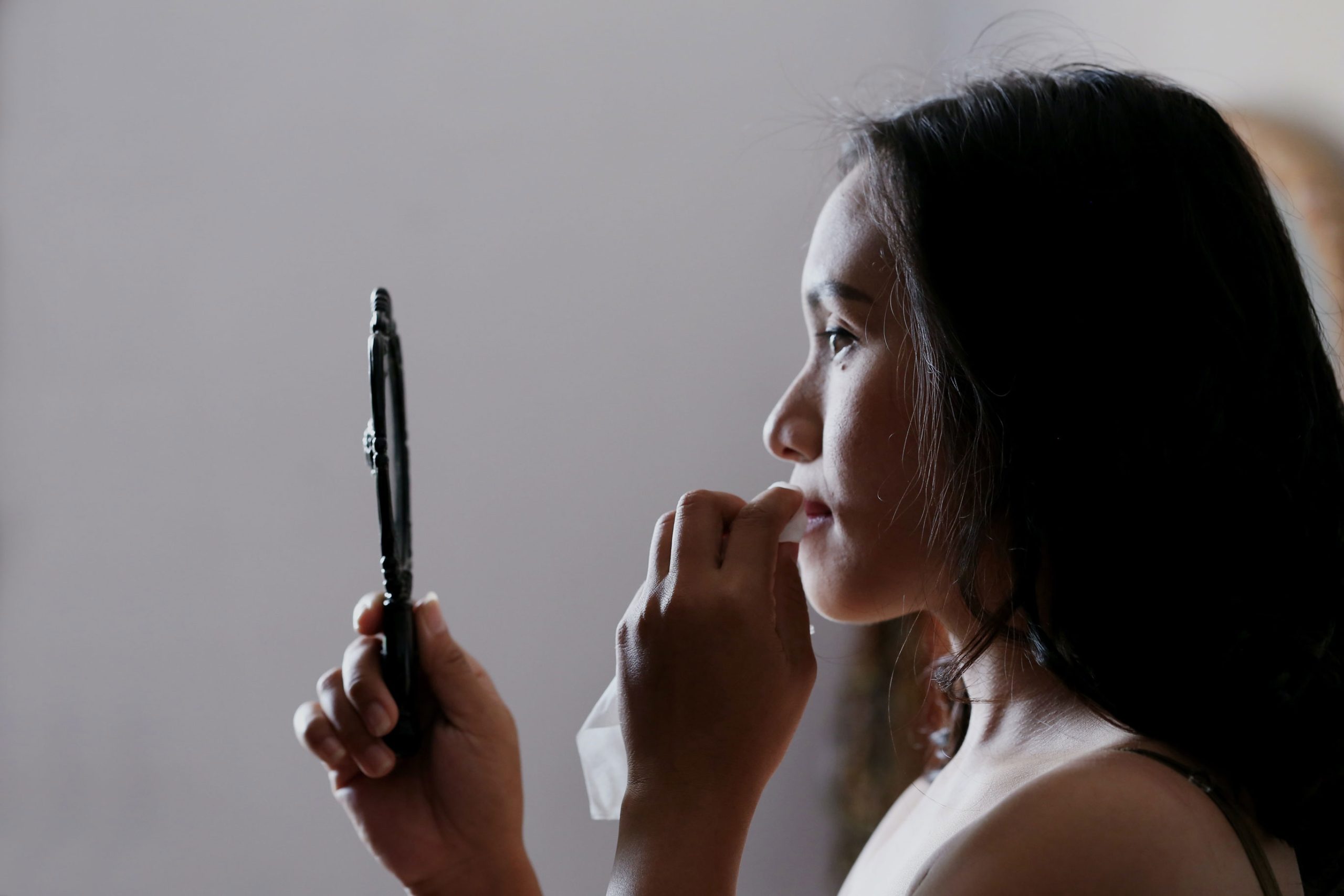 Side profile of woman looking in hand-held mirror
