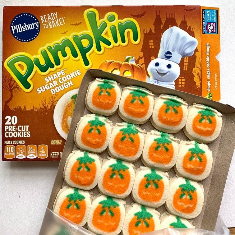 Platter of small cookies with pumpkins printed on them in front of box they came in