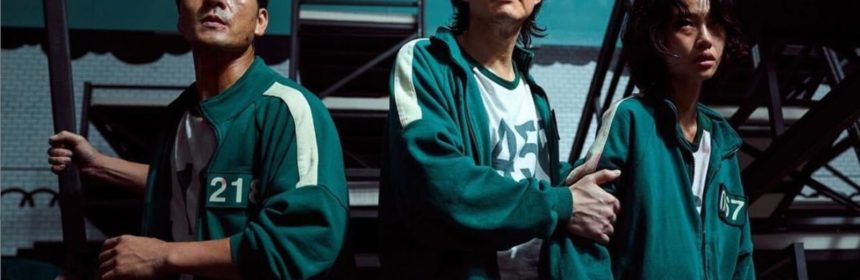 Screencap of Netflix series "Squid Game" showing 3 characters wearing green jumpsuits