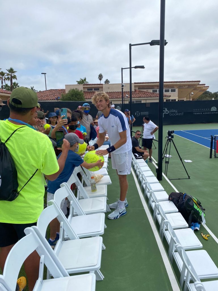 Tennis player talking with fans on a tennis court