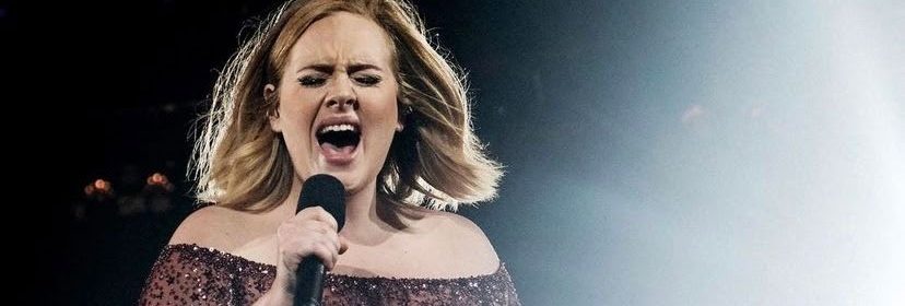 Adele singing on stage with bright lights
