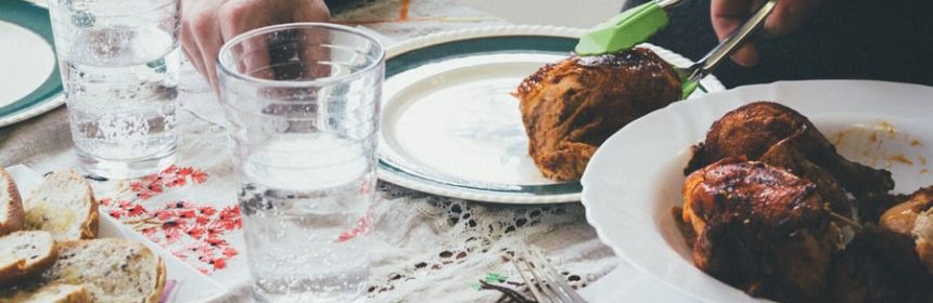 Dinner table set with someone serving chicken