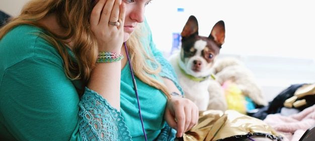 Woman working on a laptop with pet dog sitting beside her