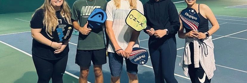 Group of pickleball players standing on court