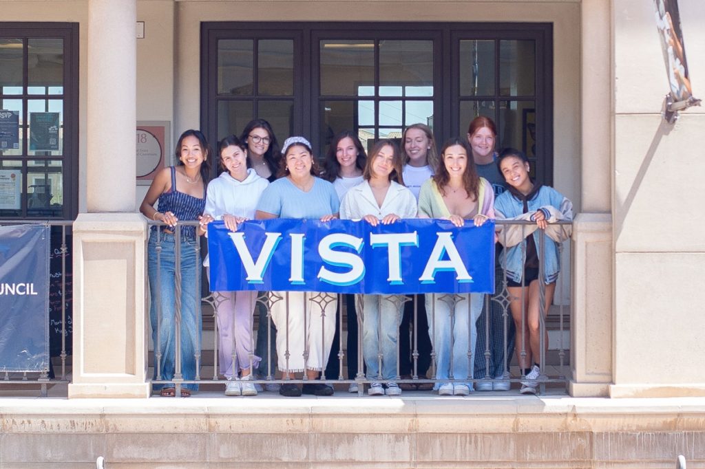 Group of Vista staff members standing in front of a sign