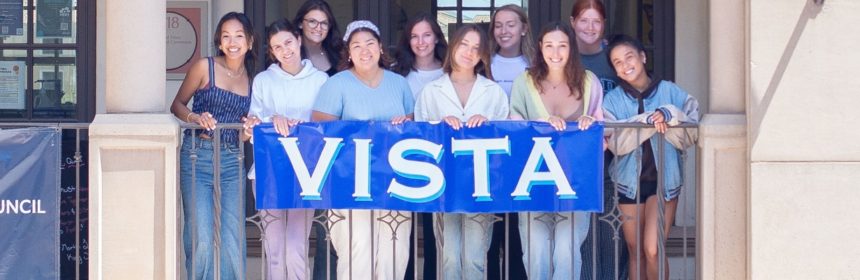 Group of Vista staff members standing in front of a sign