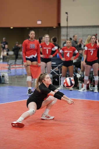girl on a volleyball court about to hit a ball.