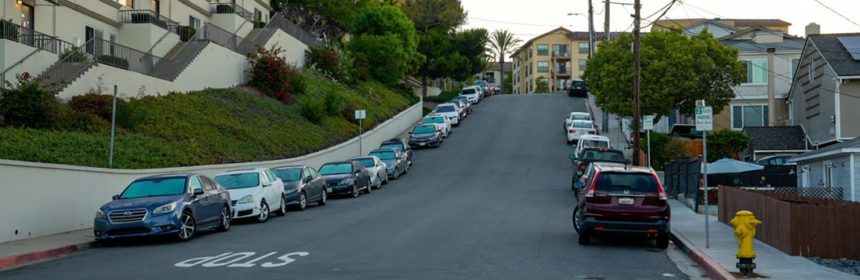 photo of road that is going up with cars on the side