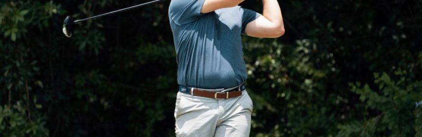 man in hat and shorts about to finish his golf swing