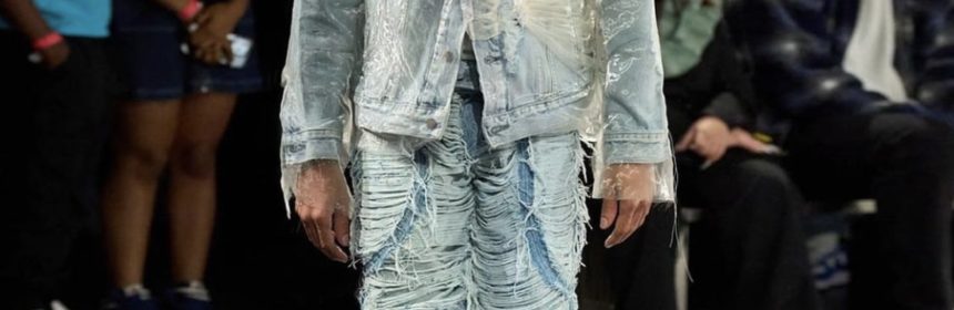 model in denim jacket and denim pants walking down the runway