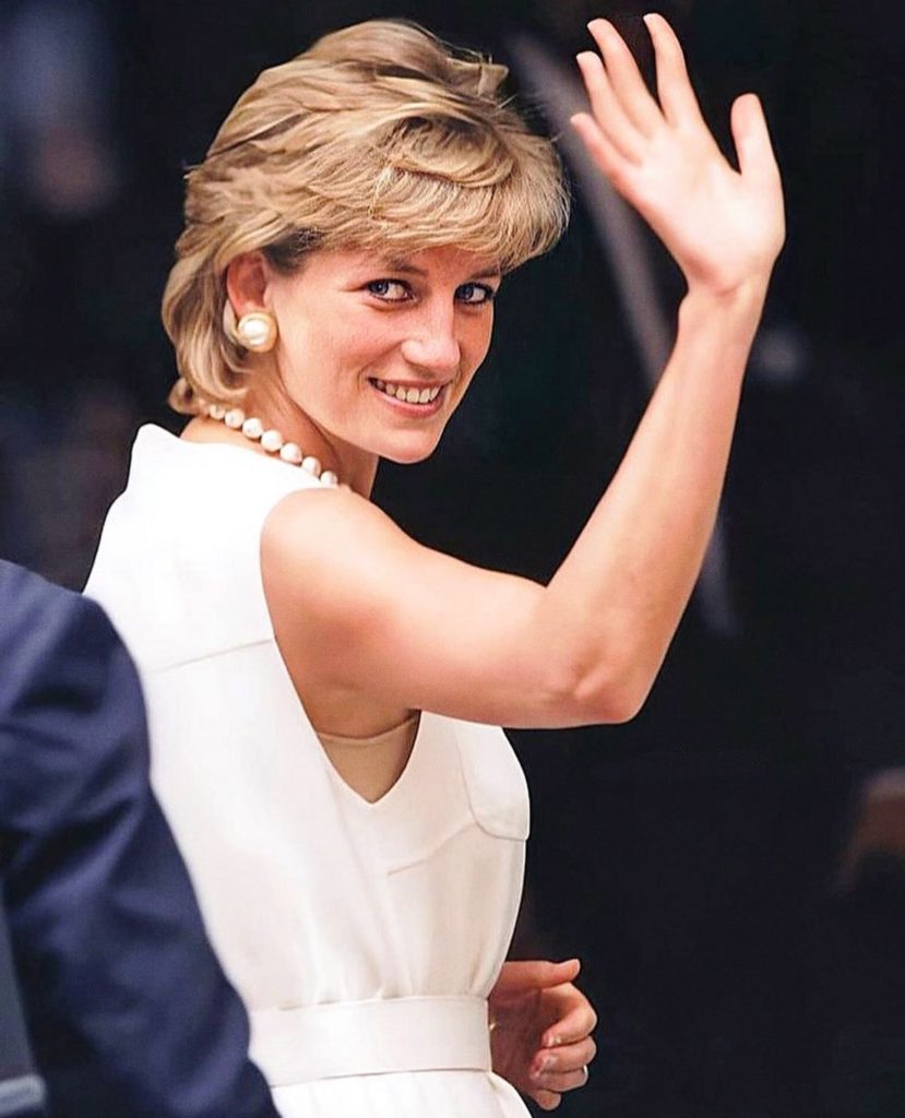 lady smiling in a white dress looking behind her and waving