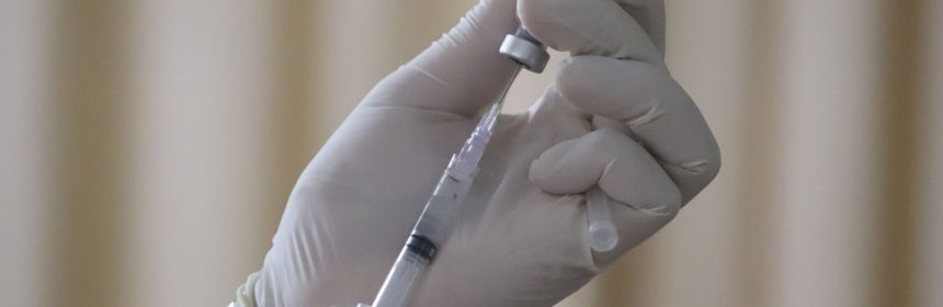 hands in gloves holding a syringe