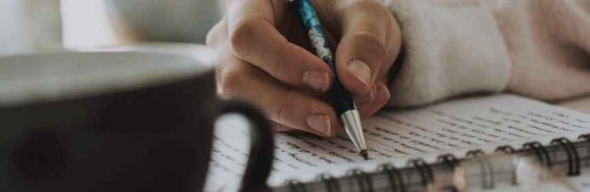 persons hand writing in a notebook