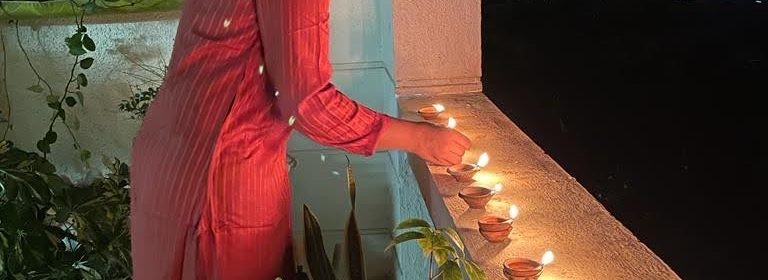 person in red dress lights candles on a ledge